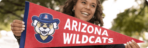 Student smiling while holding up a University of Arizona flag