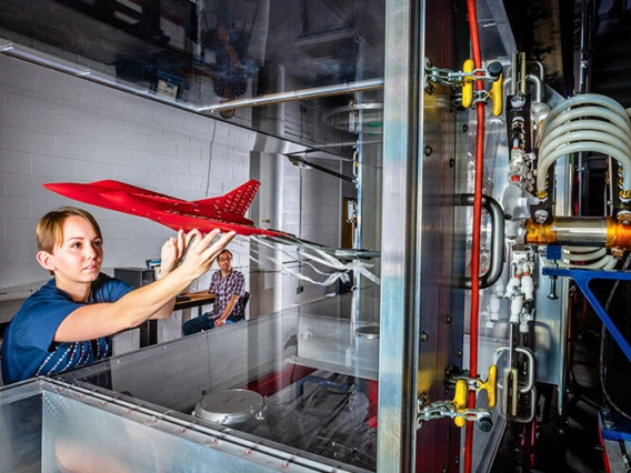 Student holding a small red aircraft model during research