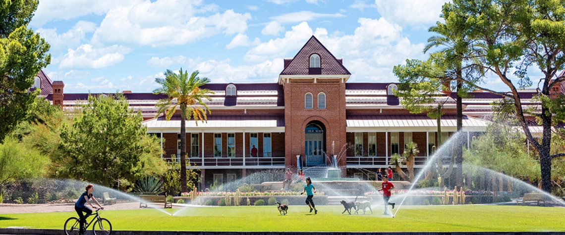 Old Main building in the background with students walking dogs on grass