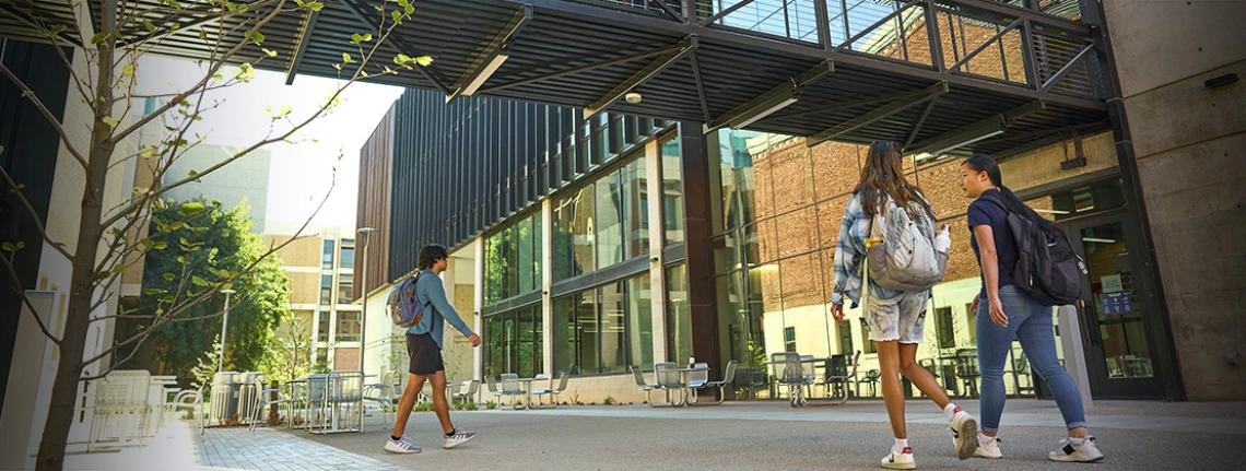 student success district - students walking under walkway bridge of new building