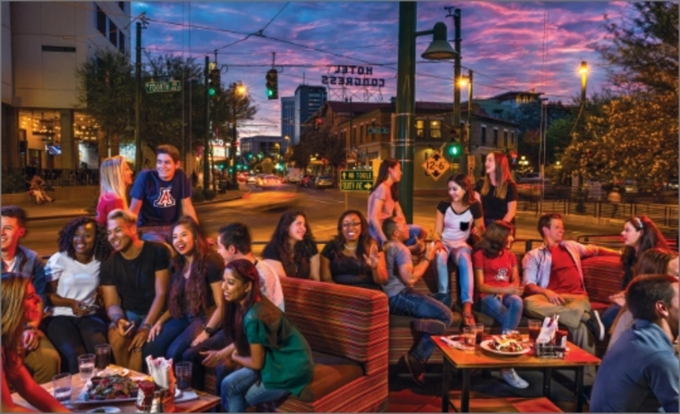 Students enjoying outdoor seating at a restaurant at dusk